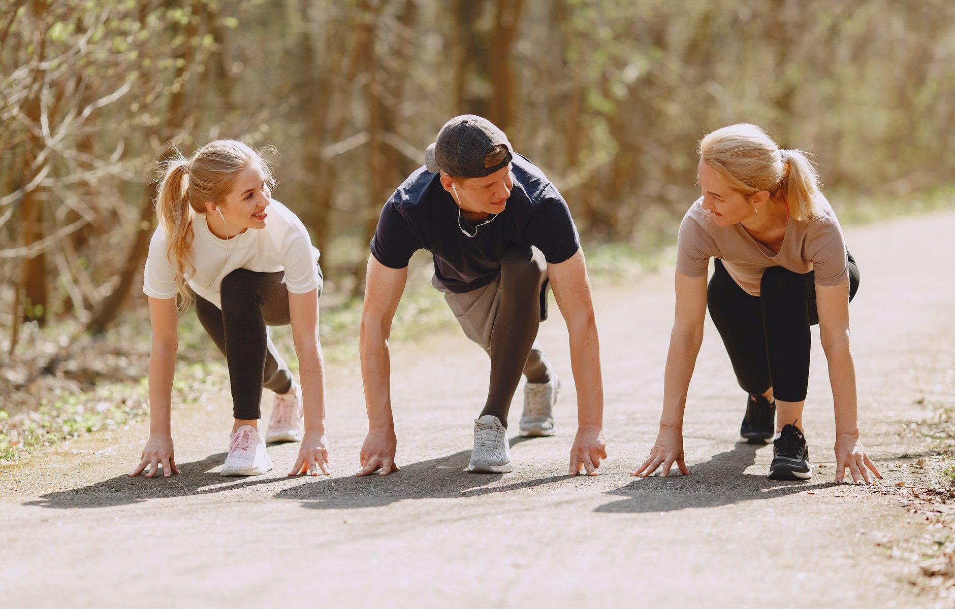 happy sportspeople of different ages preparing to run in forest