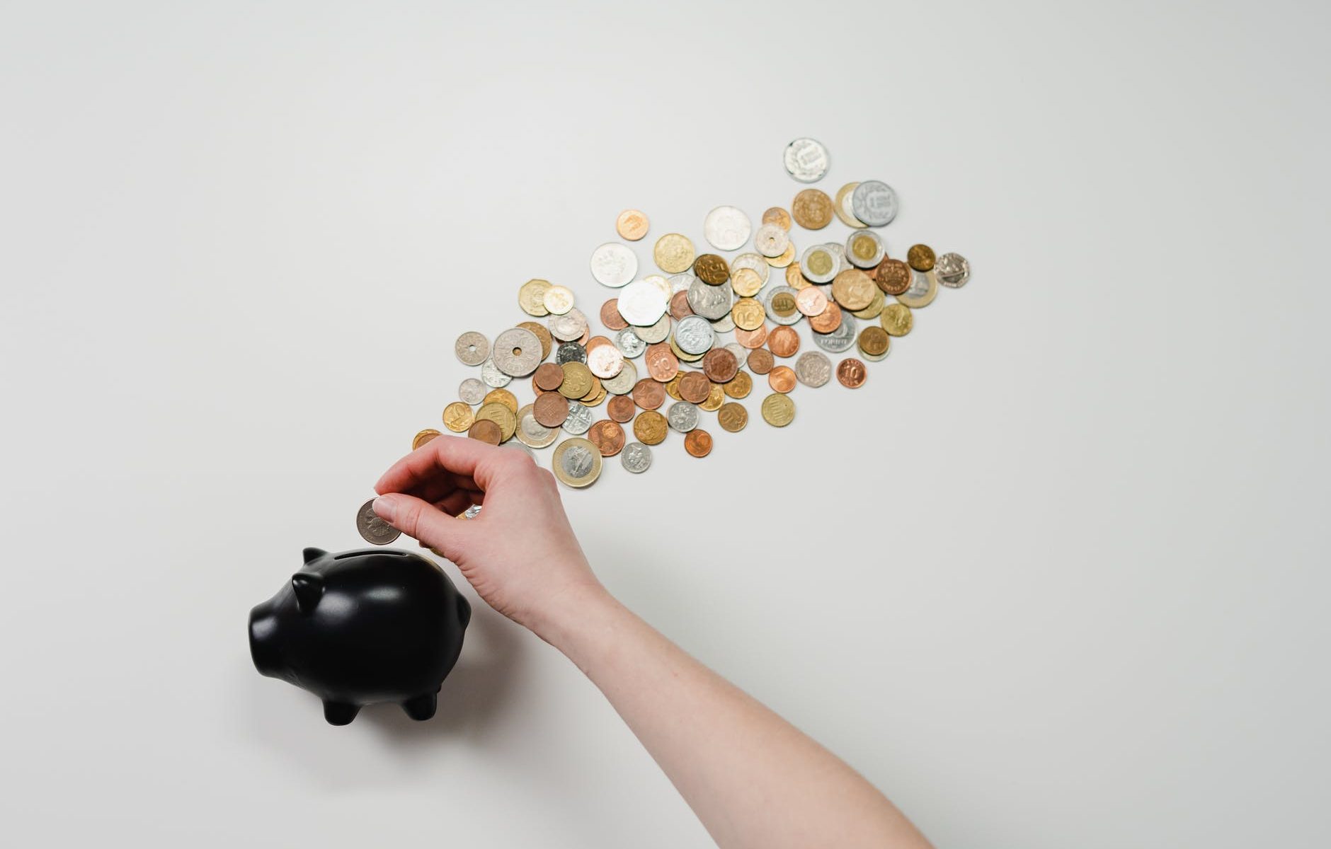 person putting coin in a piggy bank