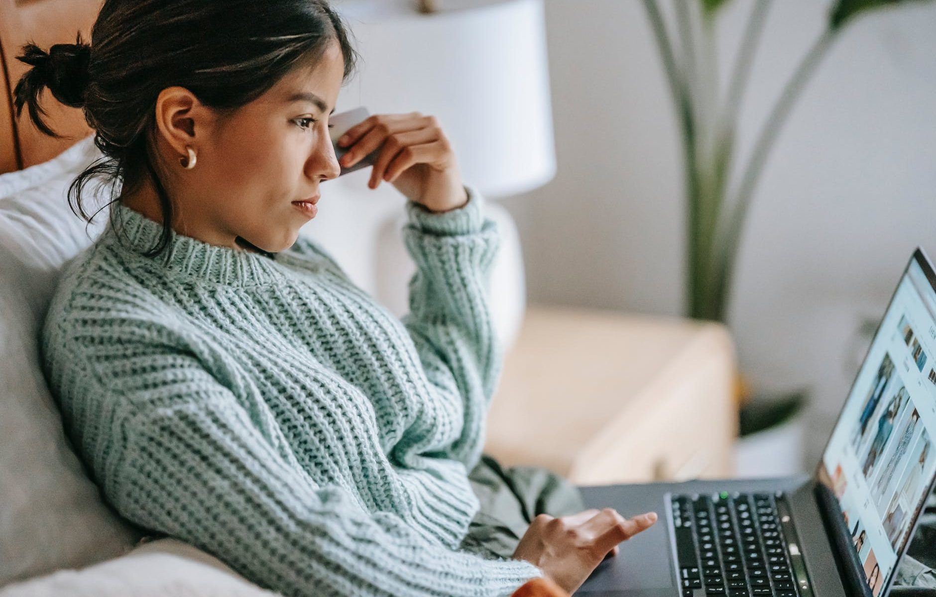 focused young ethnic woman with credit card and laptop