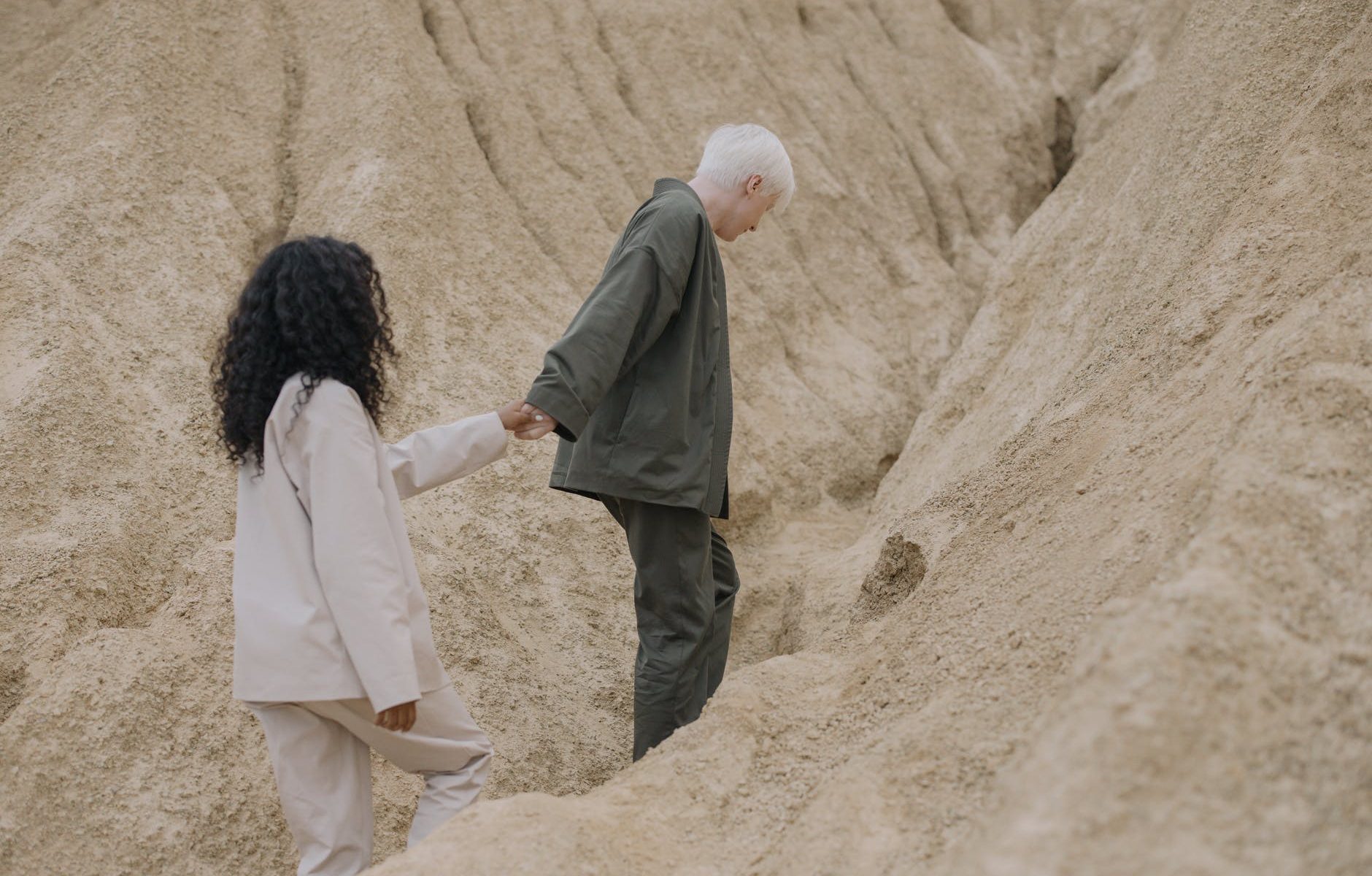 couple holding hands while walking on sand