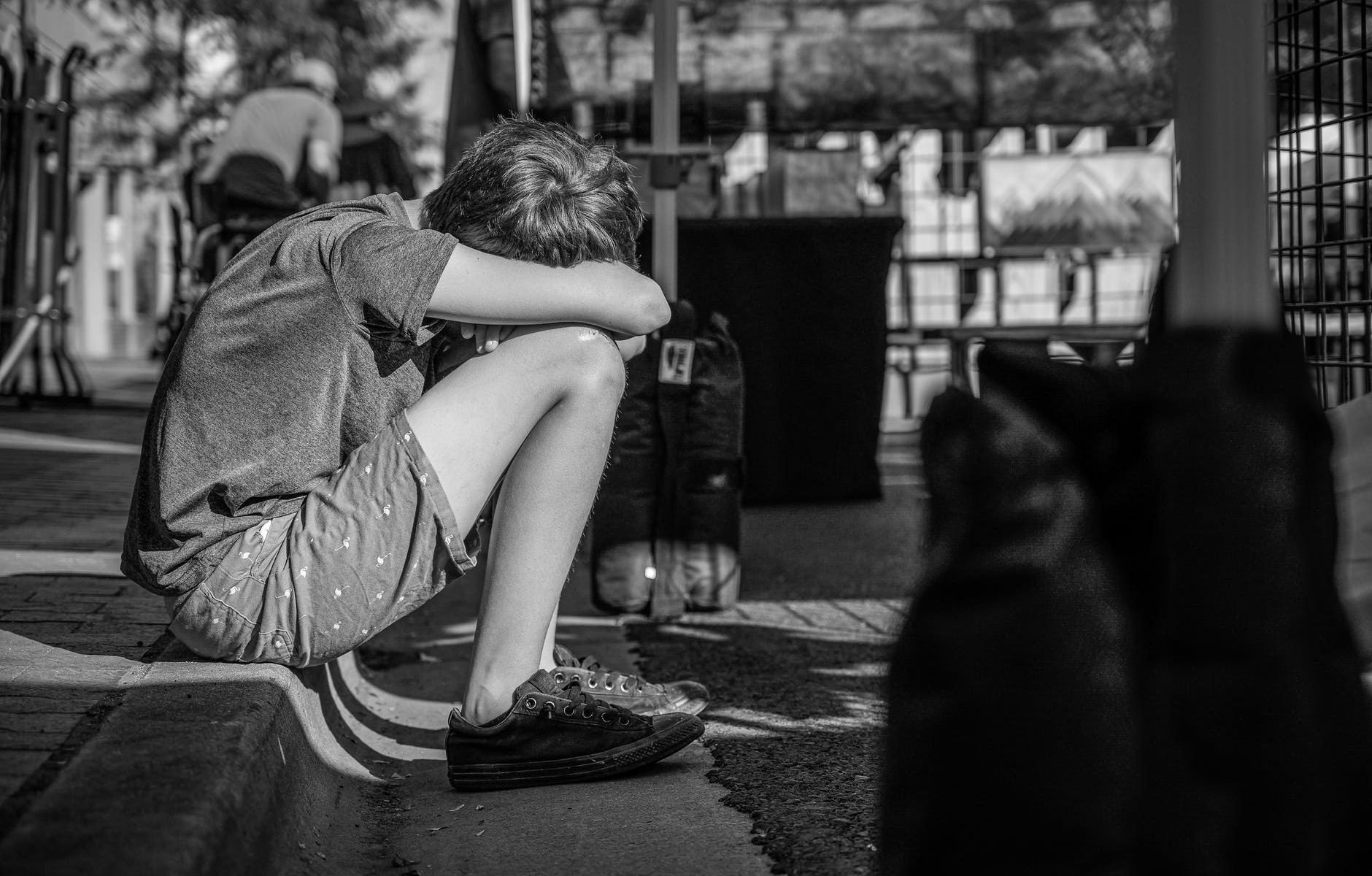 monochrome photo of person sitting on curb