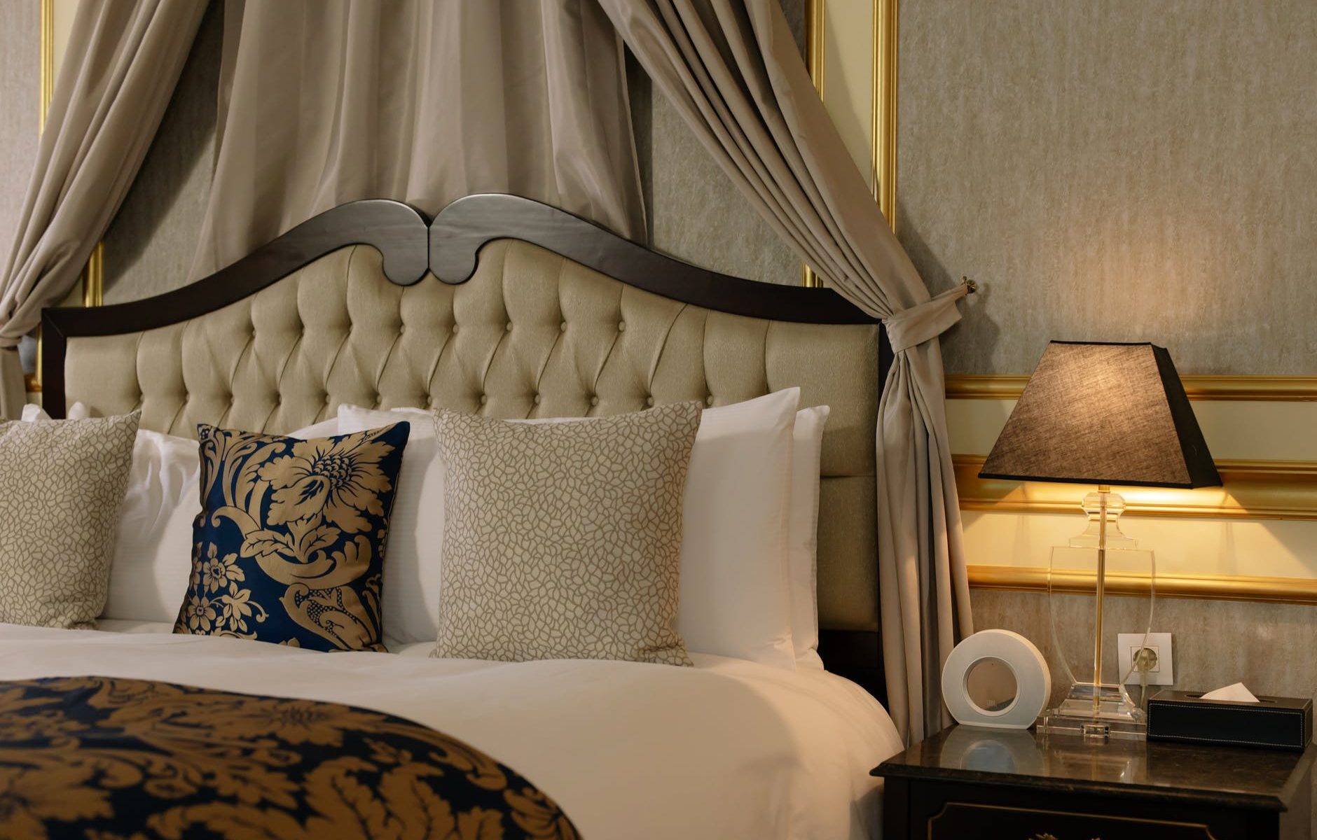 classic wooden bed beside a black side table with lighted night lamp