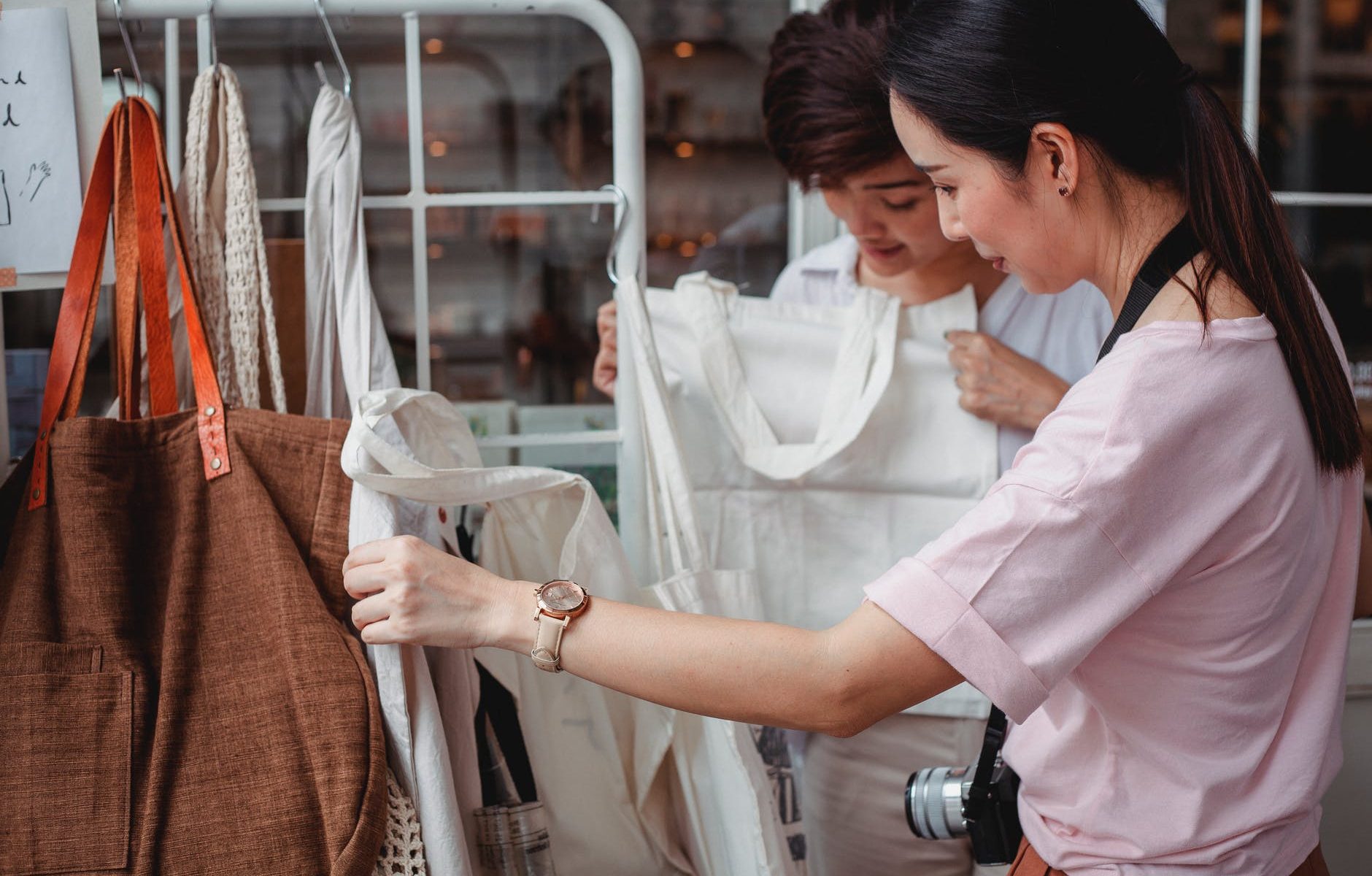 trendy young asian women choosing cotton bags in fashion boutique