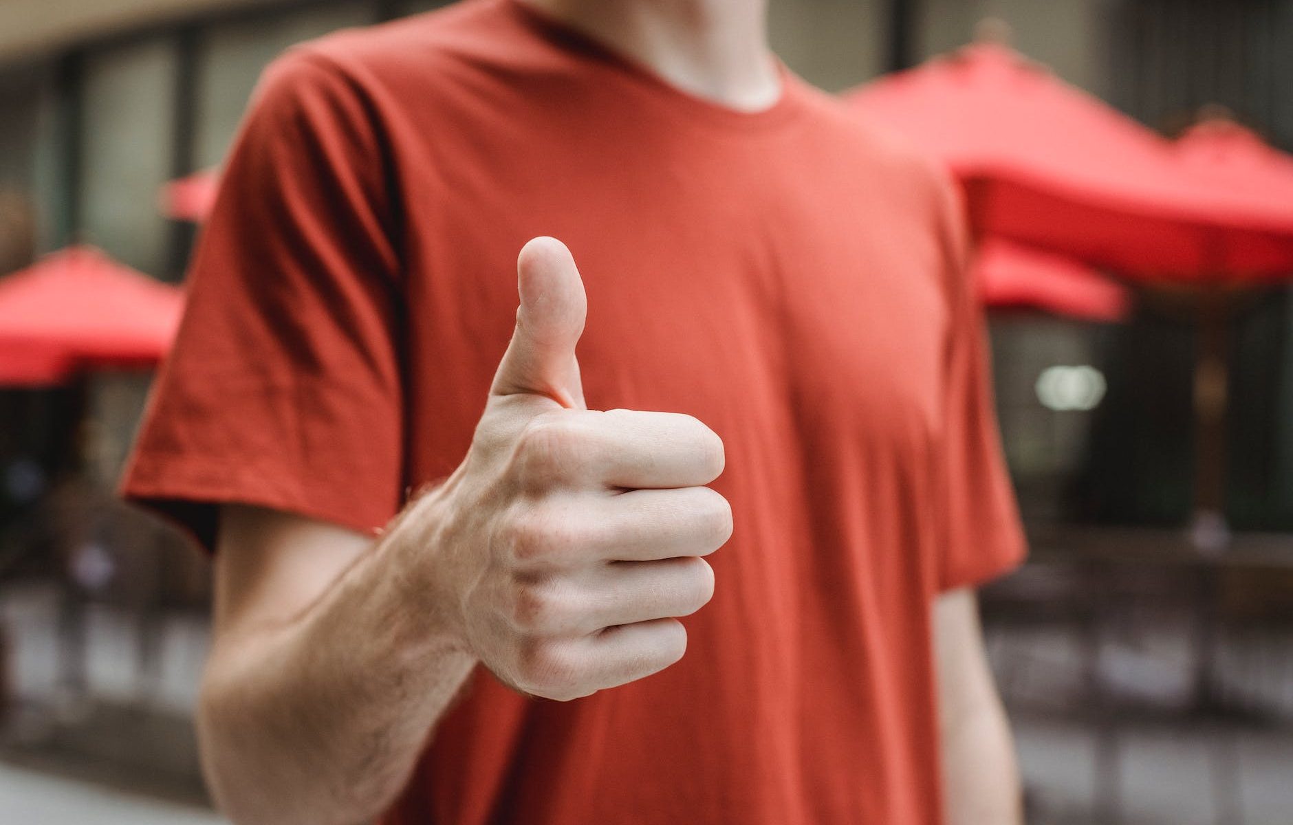 unrecognizable man showing thumb up on city street