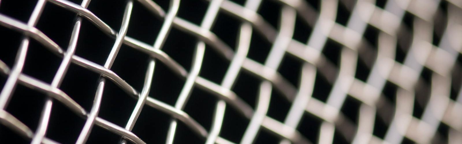 Detailed close-up of metal wire mesh pattern with a blurred background, showcasing texture and structure.