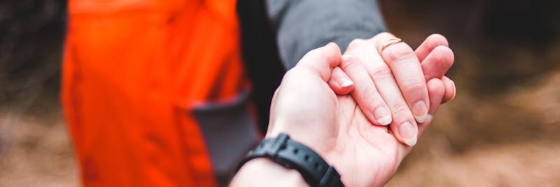 A couple holding hands while exploring an outdoor forest area.